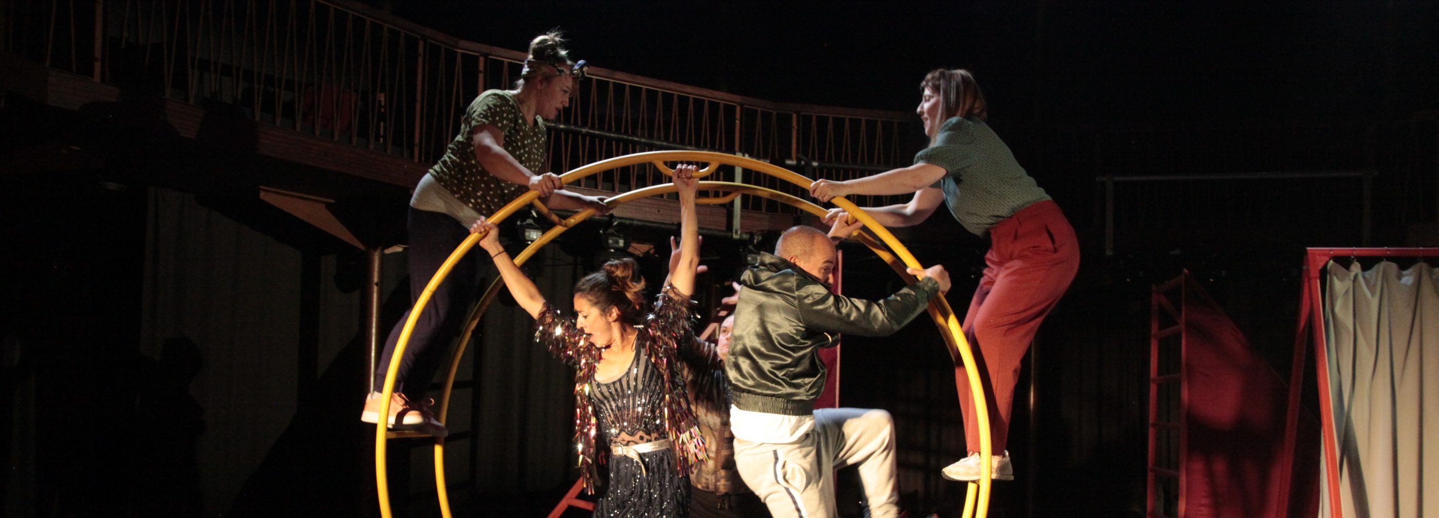 A group of performers climbing on a large german wheel structure
