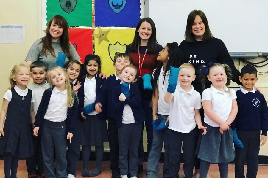 Three grown ups with a group of primary school students smiling at the camera