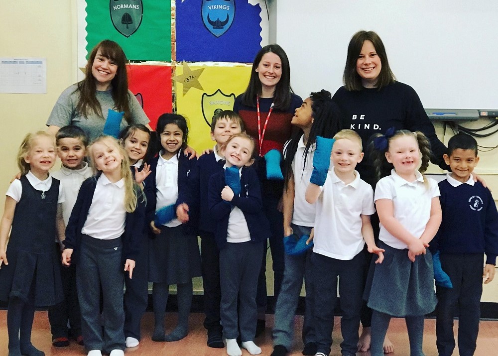 Three grown ups with a group of primary school students smiling at the camera